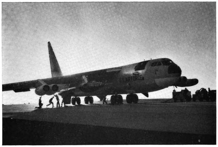 A plane with some people looking underneath the wing